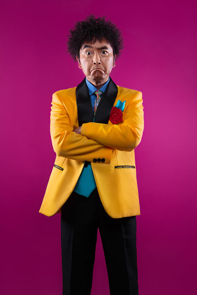 背景ピンクに黄色のタキシードのアーティスト写真