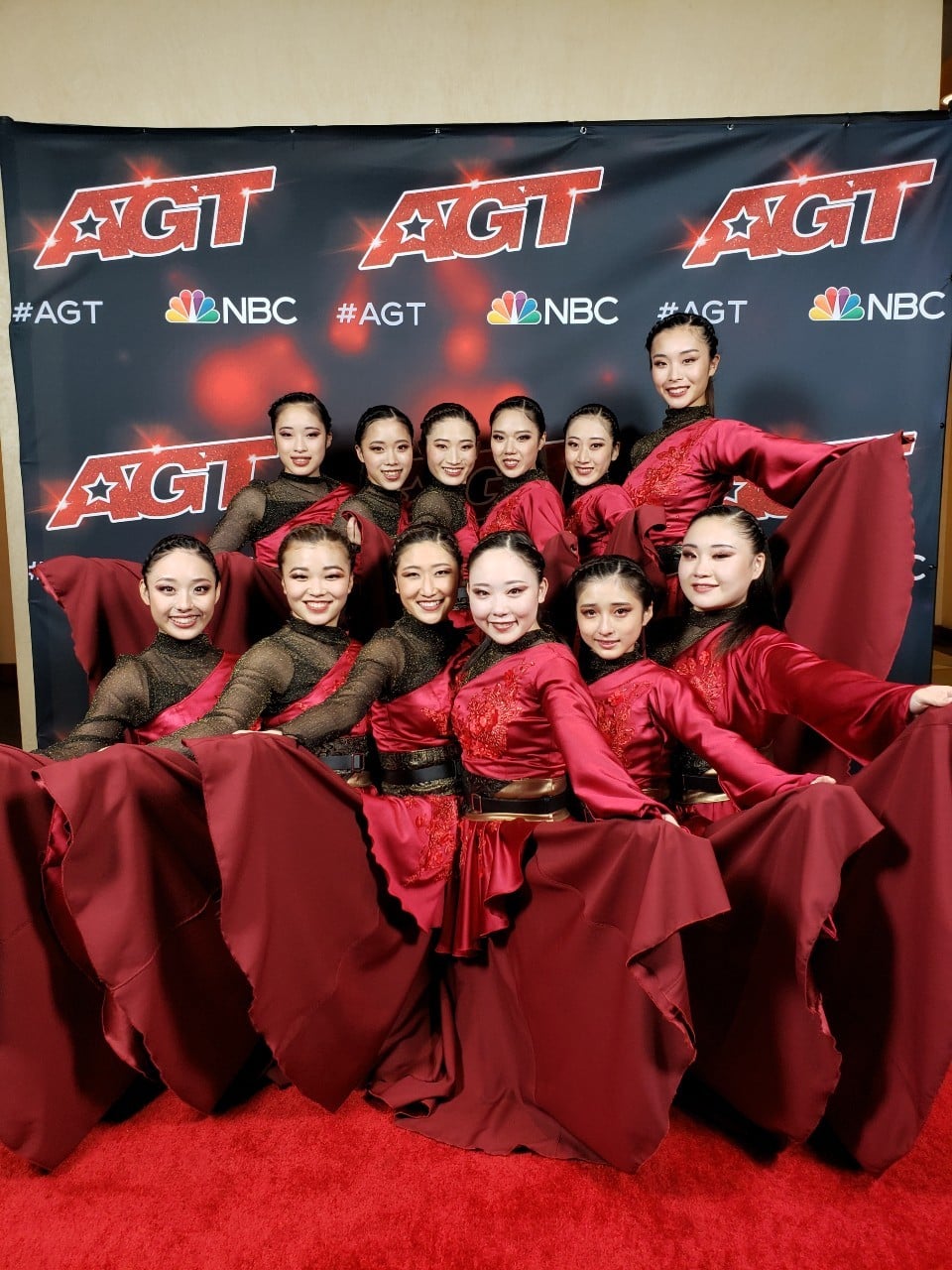 赤い衣装の12人の一輪車パフォーマー集合写真