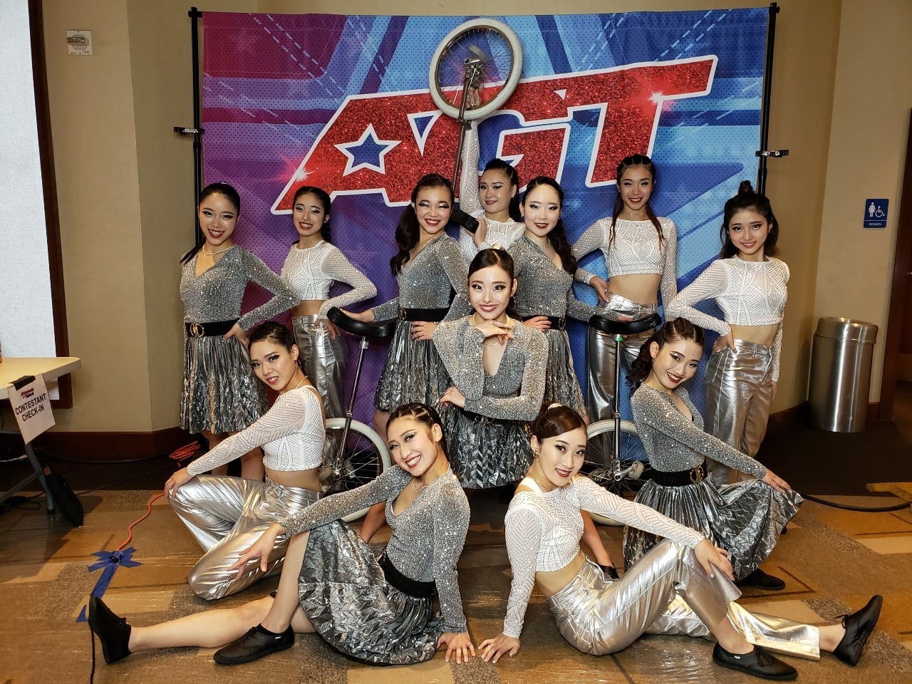 白と銀の衣装でポーズをとった12人